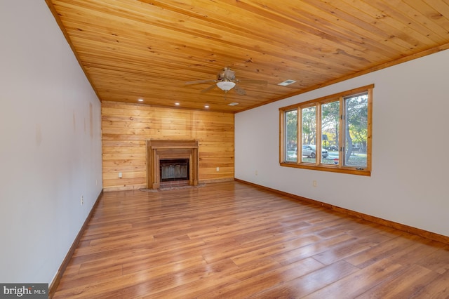 unfurnished living room with wooden walls, ceiling fan, light wood-type flooring, and wood ceiling