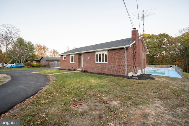 ranch-style house featuring a front yard and a fenced in pool