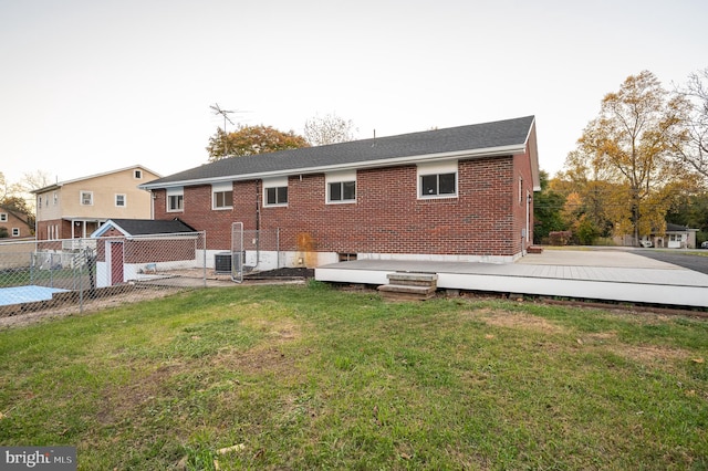 back of house featuring a lawn, a wooden deck, and central AC