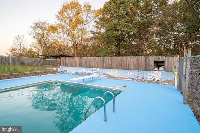 view of swimming pool with a diving board