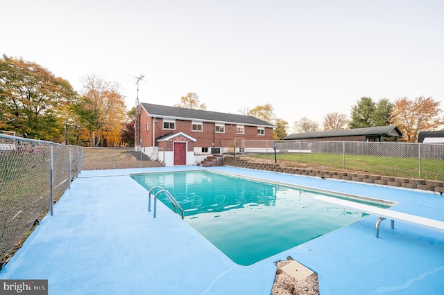 view of pool with a patio and a diving board