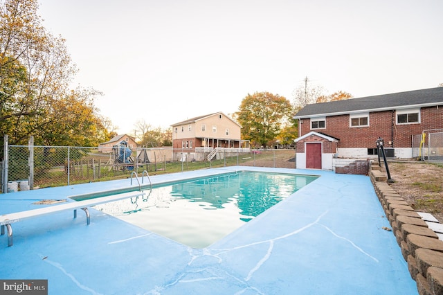 view of pool with a diving board and a storage unit