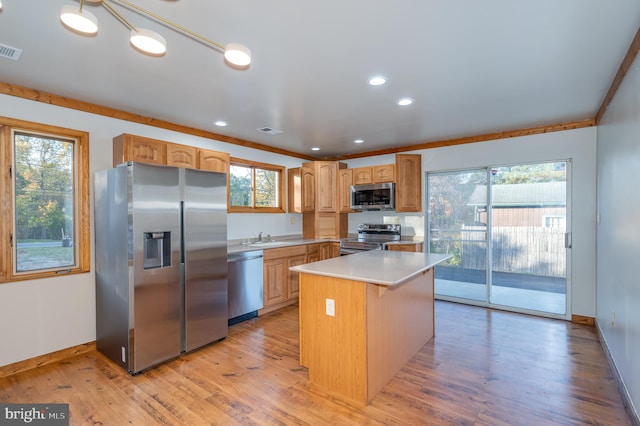 kitchen featuring appliances with stainless steel finishes, light hardwood / wood-style flooring, a kitchen island, and a wealth of natural light