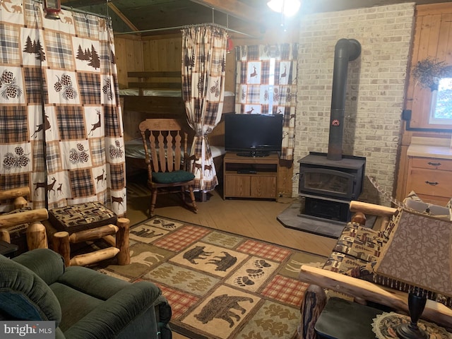 living room with a wood stove, hardwood / wood-style floors, and brick wall