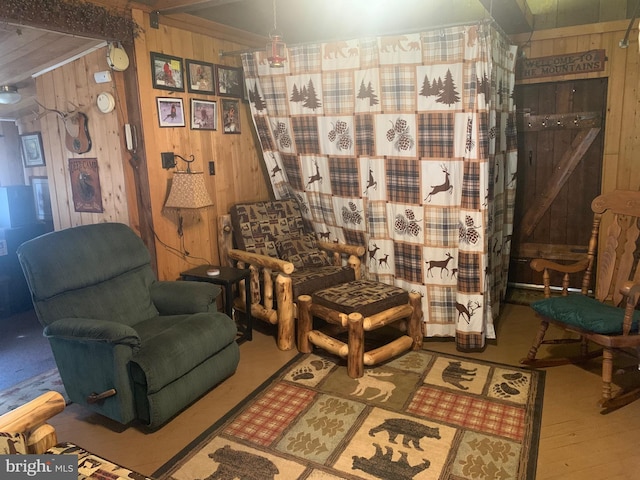 sitting room with hardwood / wood-style flooring, wood walls, and a barn door