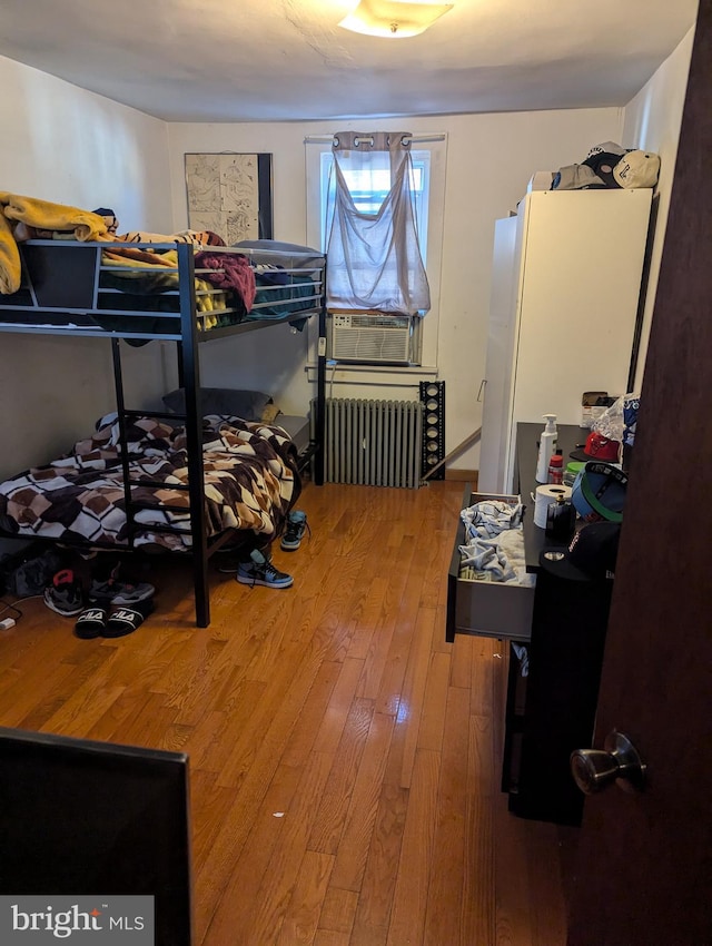 bedroom featuring cooling unit, radiator heating unit, and hardwood / wood-style flooring