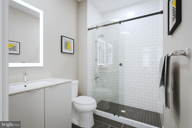 bathroom featuring toilet, an enclosed shower, vanity, and tile patterned flooring