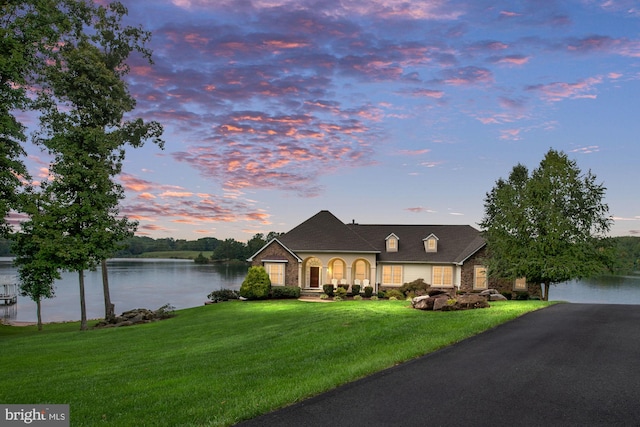 view of front of home with a lawn and a water view