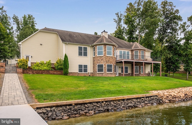 back of house featuring a lawn and a deck with water view