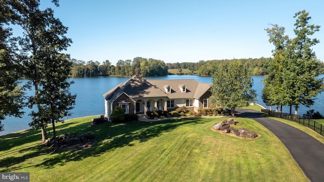 new england style home featuring a water view and a front lawn