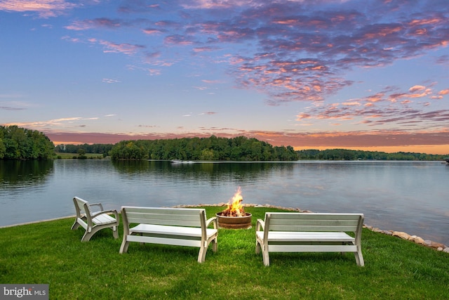 dock area with a water view, an outdoor fire pit, and a lawn