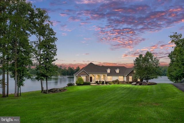 view of front of house with a lawn and a water view