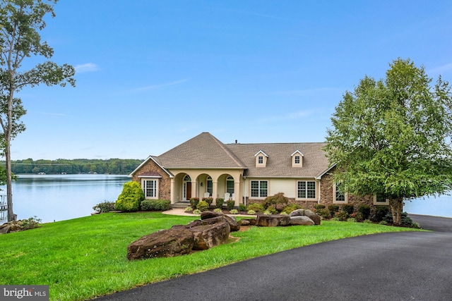 view of front of home with a front lawn and a water view