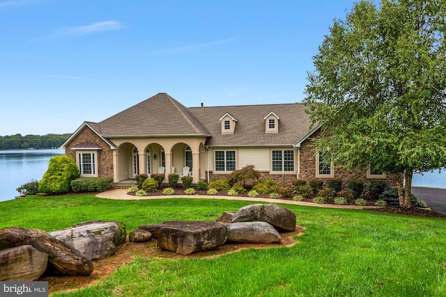 view of front facade featuring covered porch, a water view, and a front lawn