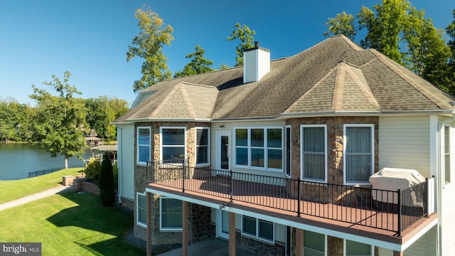 rear view of house featuring a patio area, a yard, and a water view