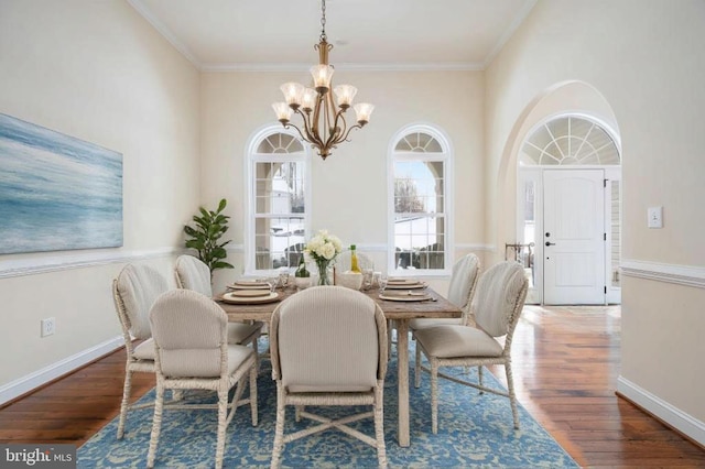 dining area featuring dark hardwood / wood-style flooring, an inviting chandelier, and crown molding