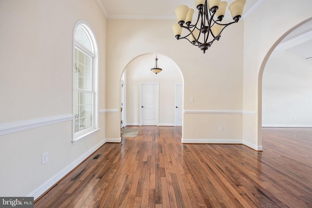 unfurnished dining area featuring dark hardwood / wood-style floors, ornamental molding, a wealth of natural light, and an inviting chandelier