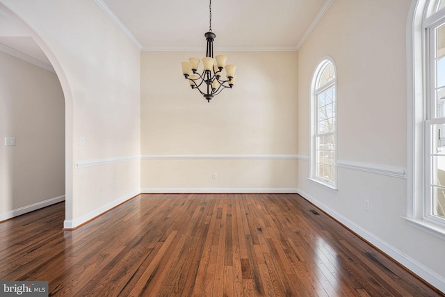 unfurnished room featuring ornamental molding, dark wood-type flooring, plenty of natural light, and a notable chandelier