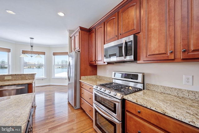 kitchen with stainless steel appliances, light stone counters, light hardwood / wood-style floors, decorative light fixtures, and ornamental molding