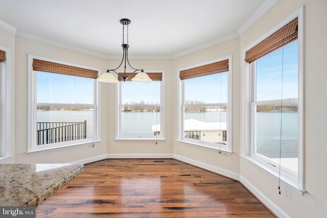 unfurnished dining area with dark hardwood / wood-style flooring, a water view, crown molding, and an inviting chandelier