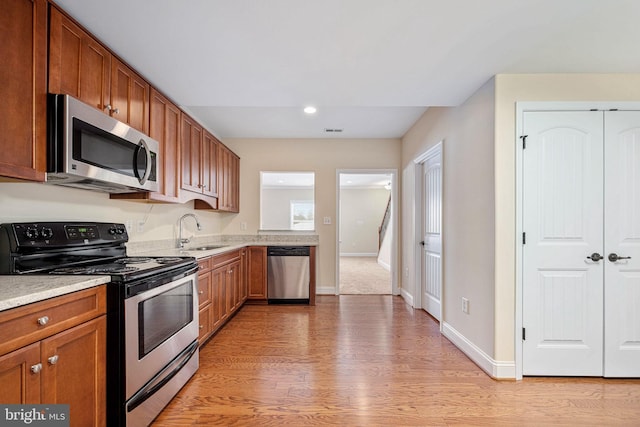 kitchen with appliances with stainless steel finishes, light wood-type flooring, and sink