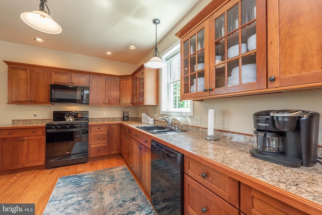 kitchen featuring sink, black appliances, pendant lighting, and light wood-type flooring