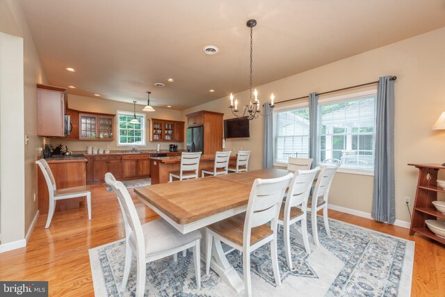 dining space featuring a wealth of natural light, sink, a notable chandelier, and light hardwood / wood-style floors