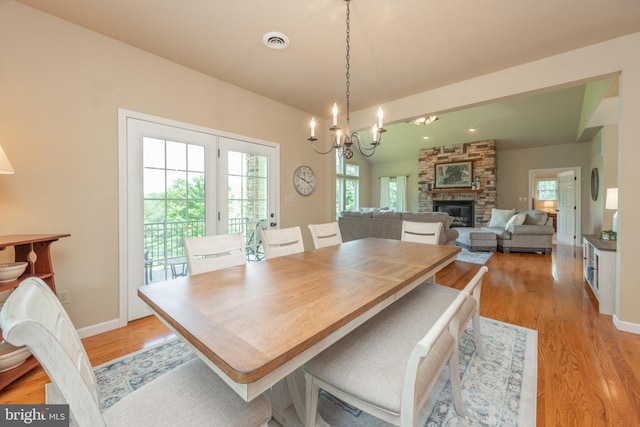 dining room featuring light hardwood / wood-style floors, a notable chandelier, and a fireplace