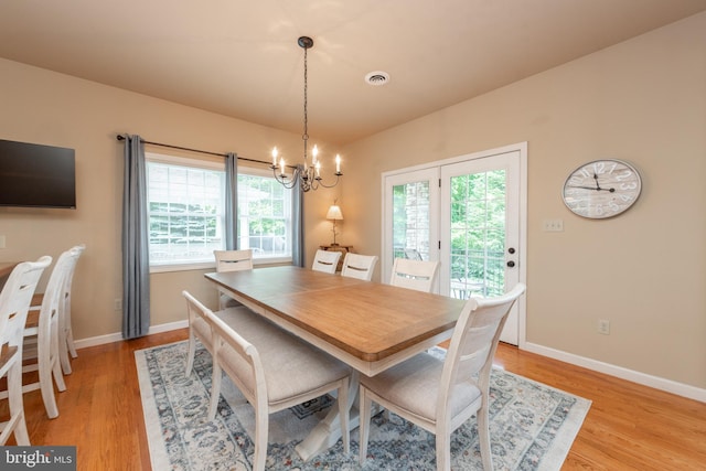 dining area with a notable chandelier, light wood-type flooring, and plenty of natural light