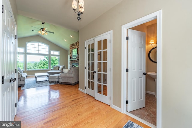 interior space featuring light hardwood / wood-style floors, ceiling fan, a stone fireplace, and vaulted ceiling