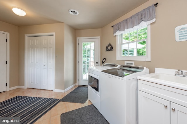 washroom featuring sink, light tile patterned floors, cabinets, and washer and clothes dryer