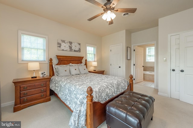 carpeted bedroom featuring multiple windows, ensuite bath, and ceiling fan