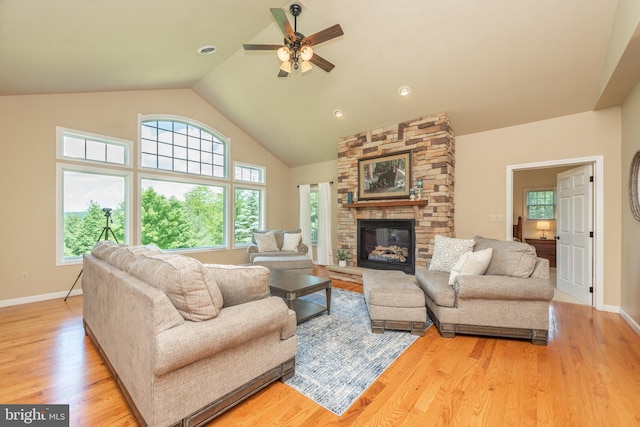 living room featuring light hardwood / wood-style floors, a stone fireplace, high vaulted ceiling, and ceiling fan