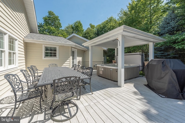 wooden deck with a hot tub and area for grilling