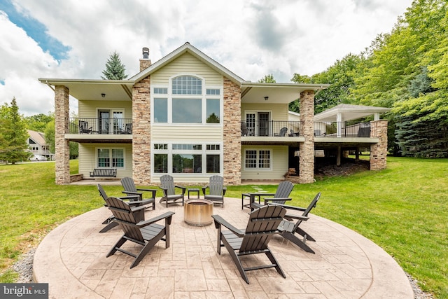 rear view of property with a patio area, a fire pit, a yard, and a balcony