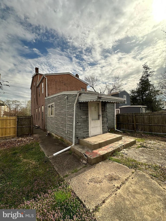 back of house with fence and stone siding