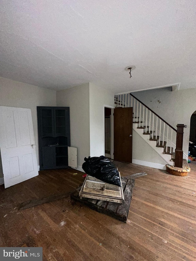 living room with baseboards, wood finished floors, and stairway