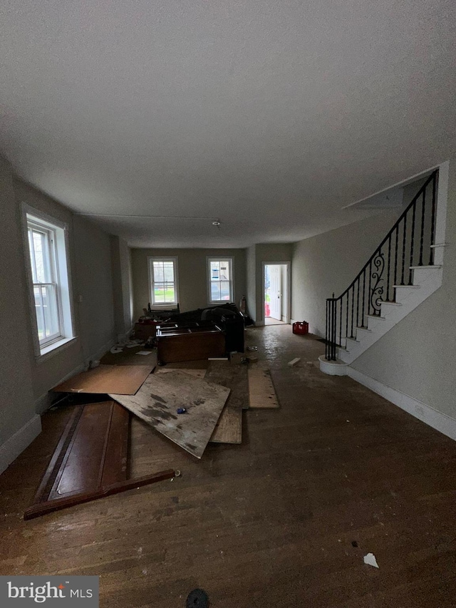living room featuring baseboards, wood finished floors, and stairs