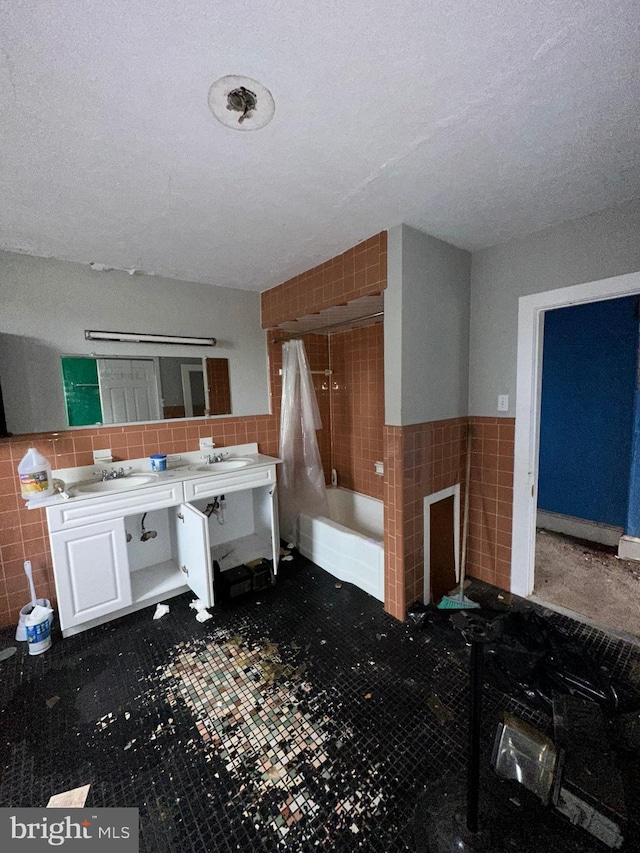 bathroom featuring vanity, tile walls, a textured ceiling, and shower / bathtub combination with curtain