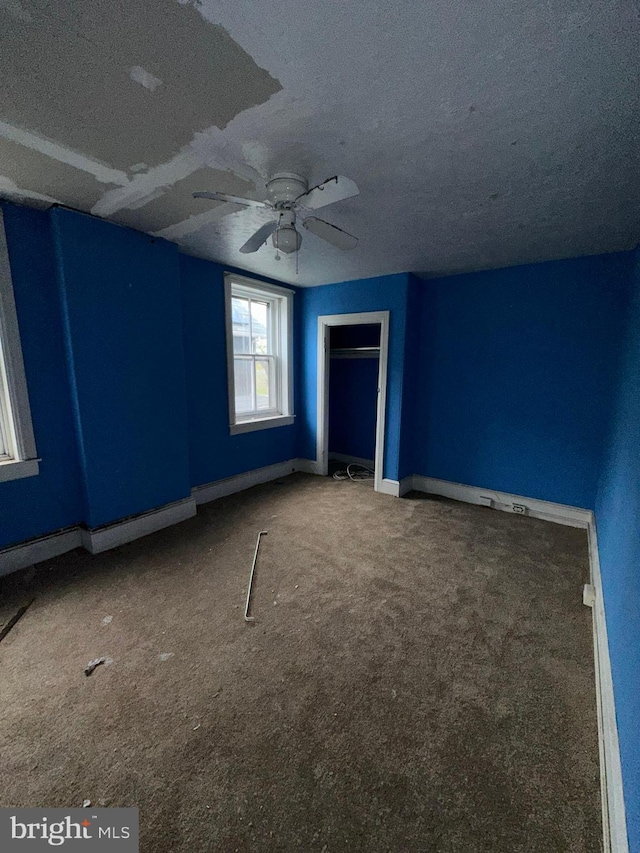 unfurnished bedroom with baseboard heating, a textured ceiling, carpet floors, and ceiling fan