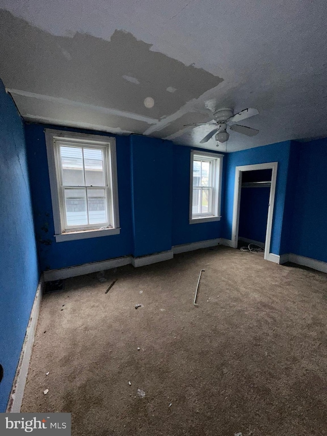 unfurnished bedroom with carpet, multiple windows, and ceiling fan