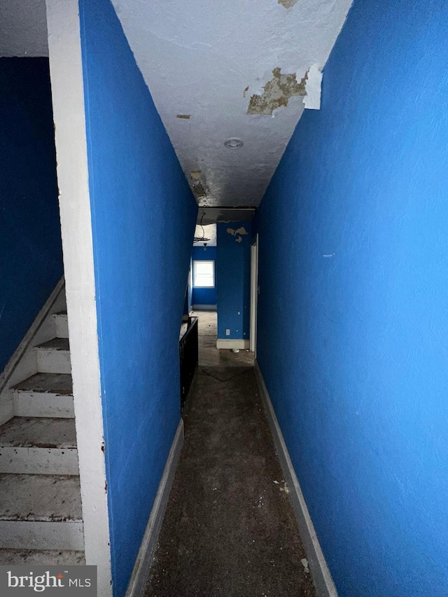 corridor featuring stairs and baseboards