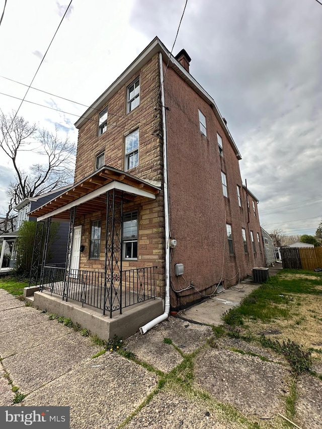 view of side of property featuring a chimney, central AC unit, and a porch