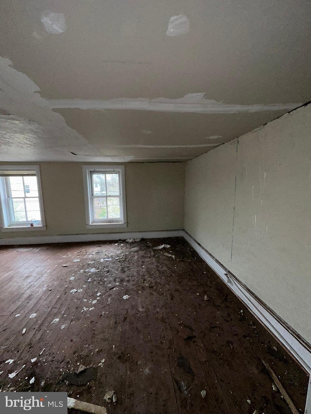 unfurnished room with a wealth of natural light, hardwood / wood-style floors, and baseboards