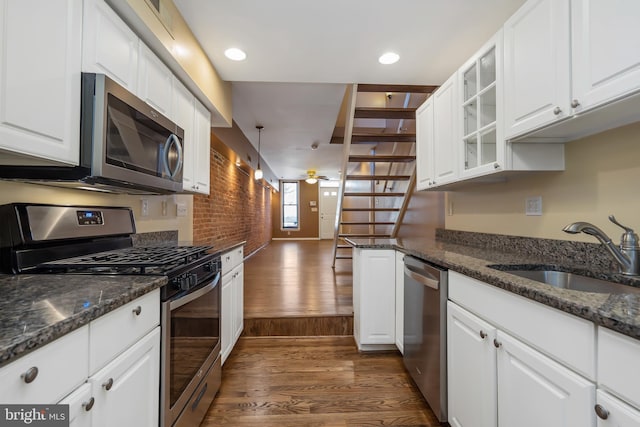 kitchen with hanging light fixtures, white cabinetry, dark wood-type flooring, sink, and stainless steel appliances