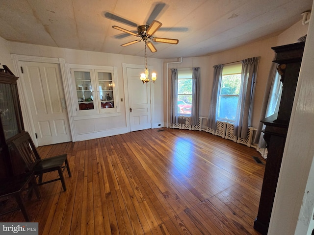 interior space with ceiling fan with notable chandelier and wood-type flooring