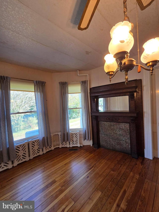 unfurnished living room with a textured ceiling, hardwood / wood-style flooring, and an inviting chandelier