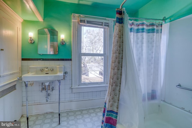 bathroom with sink, shower / bath combination with curtain, and tile walls