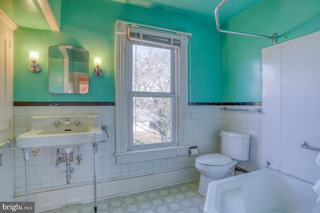 full bathroom featuring  shower combination, toilet, sink, and tile walls