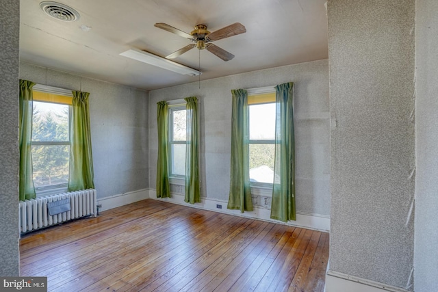 empty room featuring ceiling fan, radiator heating unit, and light hardwood / wood-style flooring